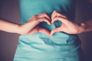 Close-up of stomach with person making heart symbol over stomach