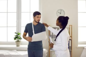 Physiatrist conducts medical examination on patient with arm in sling in hospital setting