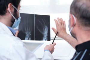 Patient places hand next to x-ray and rheumatologist points to areas of arthritis