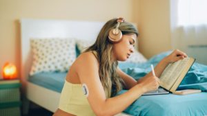 Patient with glucose monitor on arm wearing headphones and studying