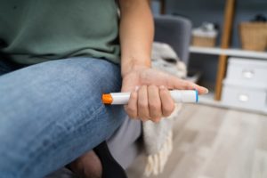 Patient sticking auto-injector into their leg to treat symptoms of anaphylaxis