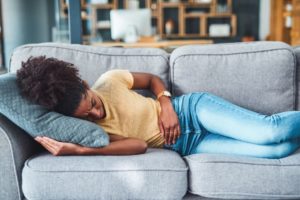Person lying on the sofa experiencing stomach pain 
