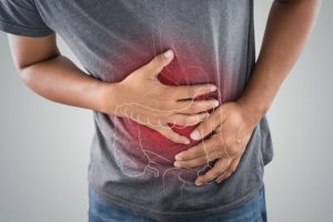 Person holding stomach in pain with a diagram of large intestine superimposed on image