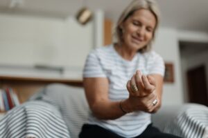 Older person sitting on bed while holding hurt wrist