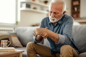 Older person suffering from hand pain caused by rheumatoid arthritis