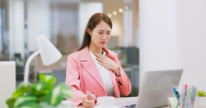 Young remote worker at laptop experiencing heartburn