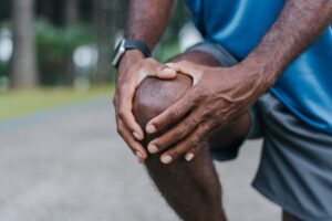 Active older person kneeling and holding painful knee