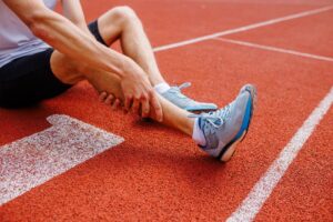 Athlete sitting on track and holding injured leg