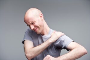 Person grimacing and holding painful shoulder
